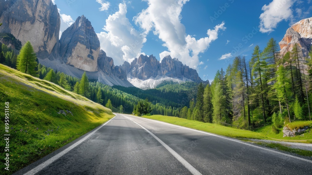 Fototapeta premium Highway in the Dolomites, Italy, on a sunny day. Lush green trees, towering rocks, and a blue sky with clouds.