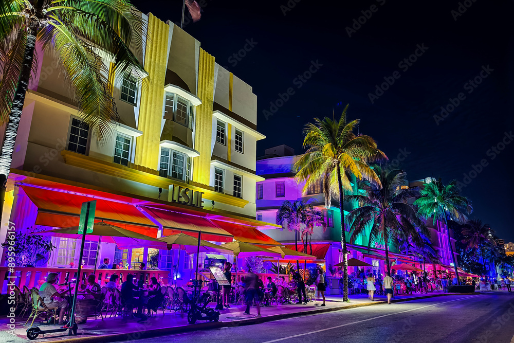Obraz premium Miami Beach, Florida - July 8, 2024: Vibrant and colorful night scene of Leslie Hotel and other historic art deco buildings on Ocean Drive in South Beach.