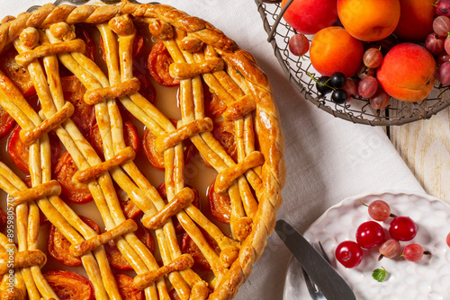 Obraz na płótnie Apricot pie decorated with dough ornament and a metal basket with fruits and berries. w salonie