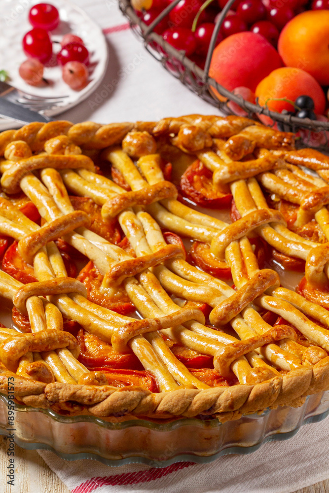 Apricot pie decorated with dough ornament and a metal basket with fruits and berries.