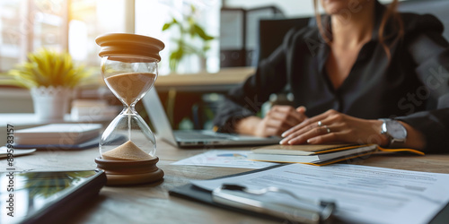 Business woman keeping track of time using an hourglass while working