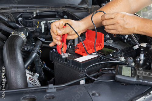 Quadro su tela Man is measuring AGM battery power of suv car by battery tester at home
