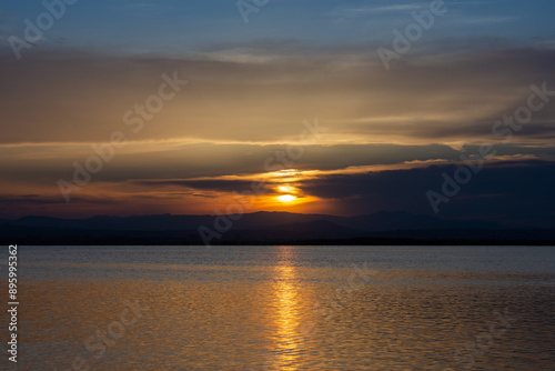 Sunset over a calm lake with the reflections of the last rays of sun on the water