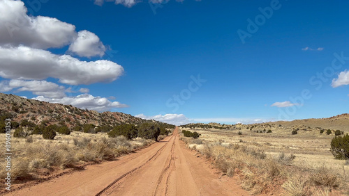 Point of View POV view of a rutted red dirt road in Capitol Reef National Park known as the Burr Trail Road. The road continues into the distance with a beautiful blue sky - Utah, USA