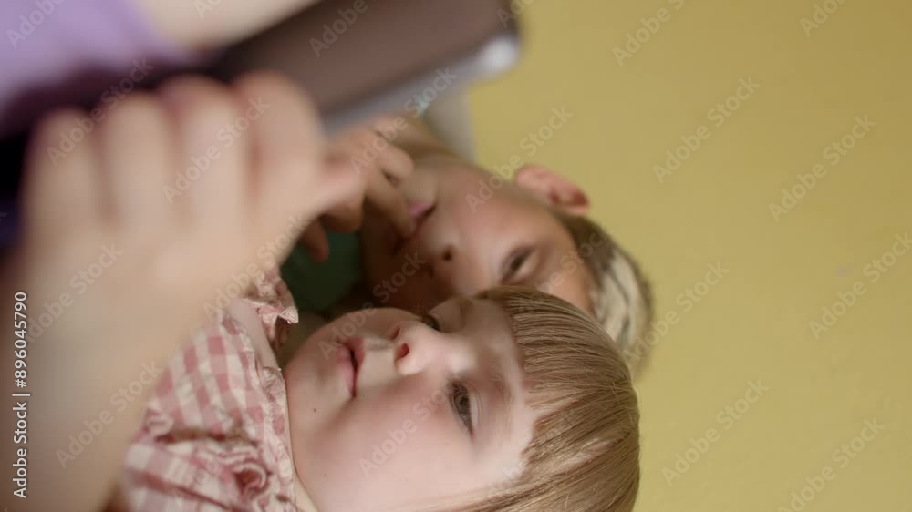 Tablets offer a wide range of entertainment content - games, movies and music - that are attractive to children of all ages. Brother and sister are looking at the tablet. Tablets offer a wide range of entertainment content - games, movies and music - that are attractive to children of all ages. Brother and sister are looking at the tablet.
