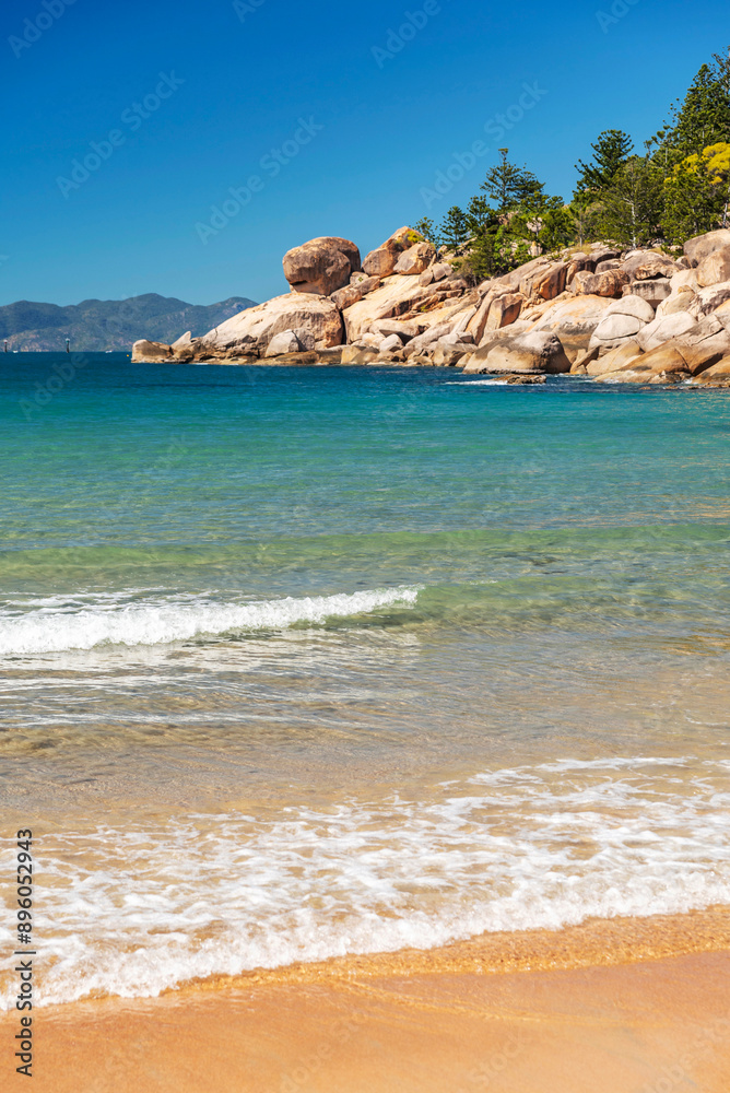 Picturesque golden sandy Alma Beach with granite boulders and turquoise water on Magnetic Island, Queensland, Australia. The island is a holiday destination 8 km offshore of Townsville.