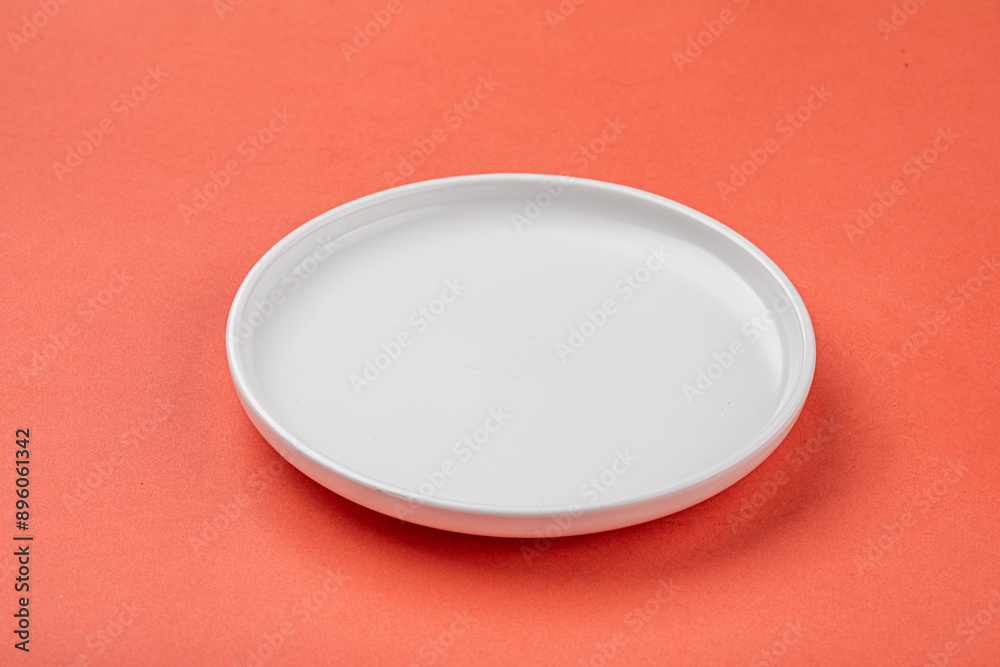 Empty white flat plate on orange background