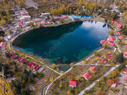 Aerial view of serene village by the lake with red roofs and autumn foliage, Skardu, Gilgit-Baltistan, Pakistan.