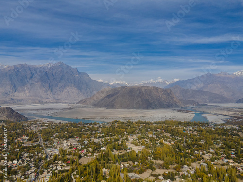 Aerial view of tranquil village by Indus River amidst snow capped peaks in Gilgit-Baltistan, Pakistan.