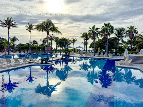 Palm trees and lush green vegetation in a tropical environment reflected in a huge pool at sunrise in the Caribbean, ideal for summer vacations and relaxation. photo