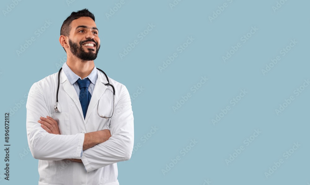 Happy Egyptian Physician Man Smiling Looking Aside Posing With Stethoscope Near Copy Space Standing In Studio Over Blue Background. Doctor's Portrait. Medical Career Concept Happy Egyptian Physician Man Smiling Looking Aside Posing With Stethoscope Near Copy Space Standing In Studio Over Blue Background. Doctor's Portrait. Medical Career Concept