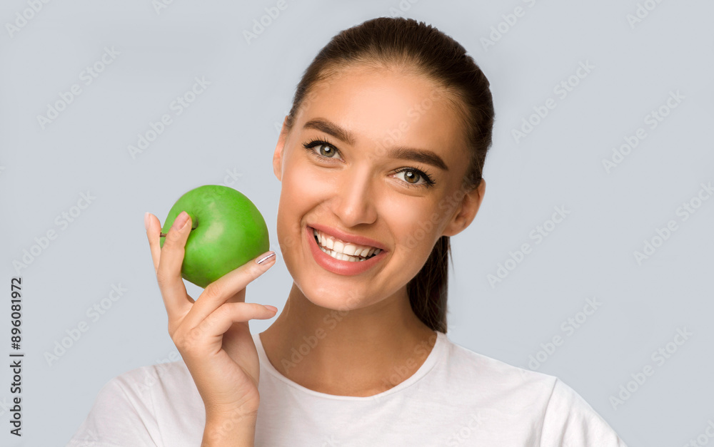 Happy Woman Holding Green Apple Smiling At Camera Standing Over White Studio Background. Isolated Happy Woman Holding Green Apple Smiling At Camera Standing Over White Studio Background. Isolated