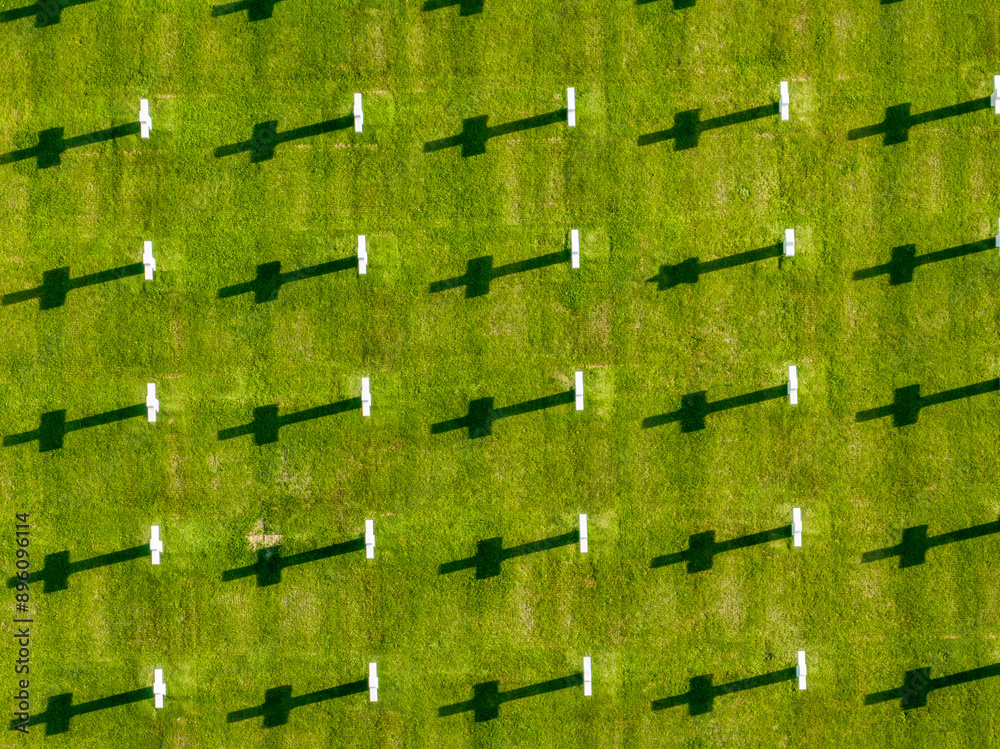 Naklejka premium Aerial view of the Normandy American Cemetery and Memorial is a World War II cemetery and memorial in Colleville-sur-Mer, Normandy, France. White cross on a green lawn