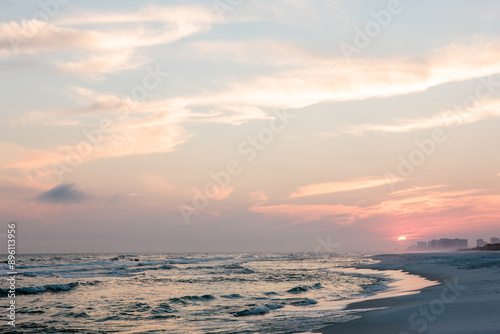 The evening sun sets in the west against the distant commercial buildings along the gulf shores just west of Topsail Hill Preserve State Park, Santa Rosa Beach, Florida in mid-April