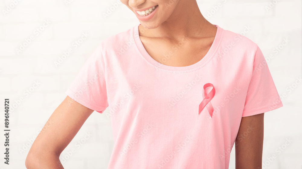 Breast Cancer. African Girl With Pink Ribbon On T-Shirt Standing Posing Over White Background. Copy Space Breast Cancer. African Girl With Pink Ribbon On T-Shirt Standing Posing Over White Background. Copy Space