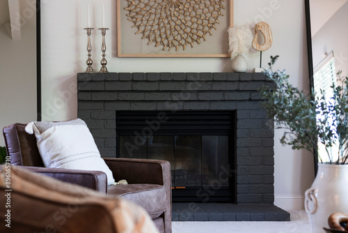 Elegant living room details of leather arm chair near fireplace with darkly painted mantel and decorative items. photo