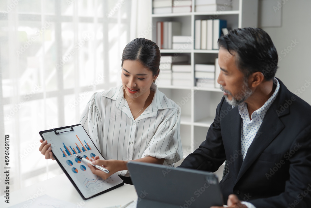 Business team collaborates while analyzing financial data using a digital tablet and charts on a clipboard Business team collaborates while analyzing financial data using a digital tablet and charts on a clipboard