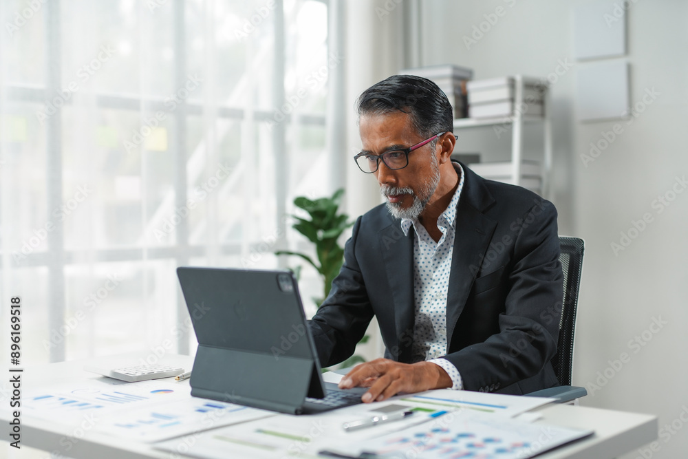 Senior executive is analyzing financial data on a tablet to create plans for business expansion