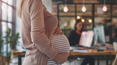 Office Work During Pregnancy. Woman with Late Pregnancy Holds Her Belly with Her Hands. The Problem of No Maternity Leave photo