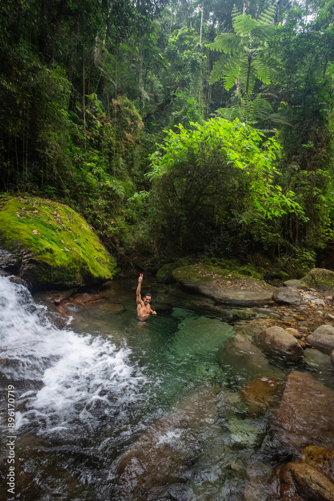 Man bathing on beautiful green waterfall in Atlantic Rainforest Man bathing on beautiful green waterfall in Atlantic Rainforest