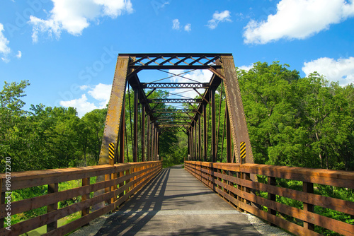 Obraz na plátně Sunny Summer day landscape of a bike trail passing over an old trestle along the Root River and Harmony-Preston Valley Trails near Preston, Minnesota