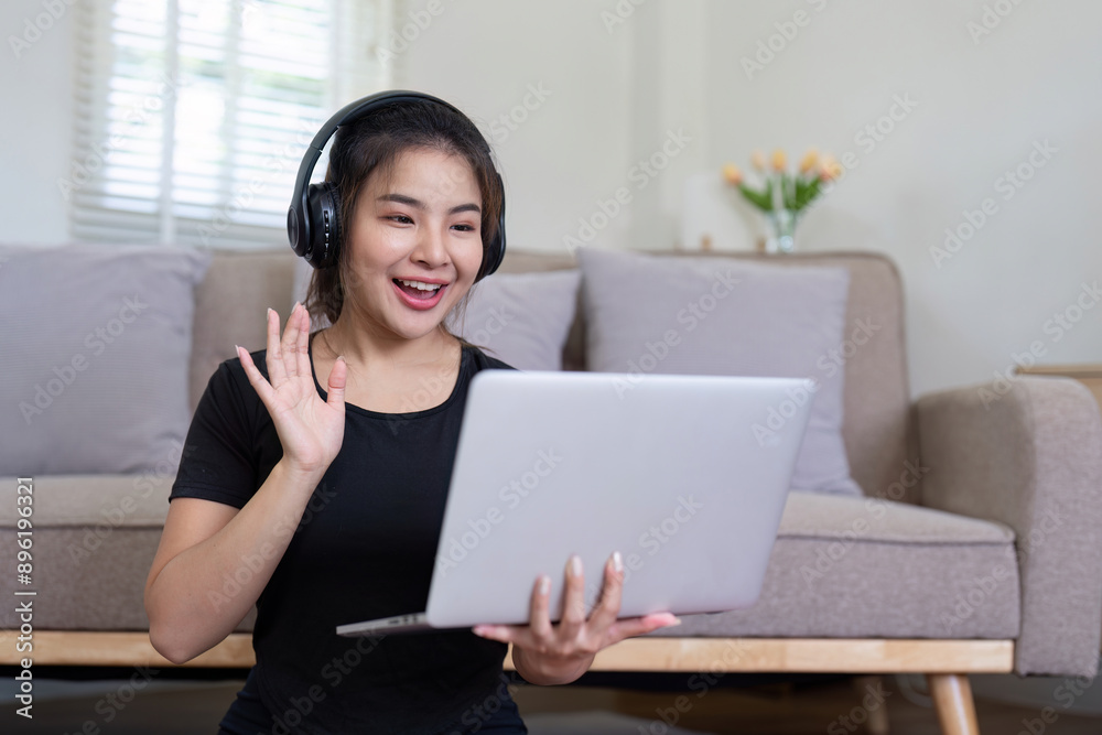 Young Woman Using Laptop and Headphones for Video Call in Modern Living Room Young Woman Using Laptop and Headphones for Video Call in Modern Living Room