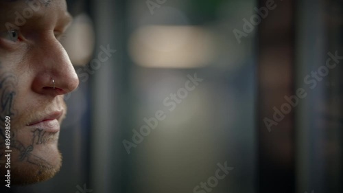 A tattooed man with face tattoos is displayed in an urban setting, accompanied by artistic elements photo