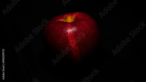 Roter Apfel mit Wassertropfen in stimmigem Licht
