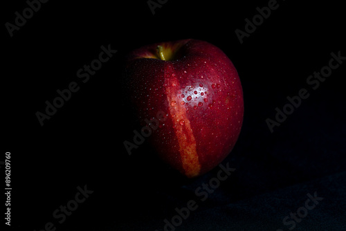 Roter Apfel mit Wassertropfen in stimmigem Licht