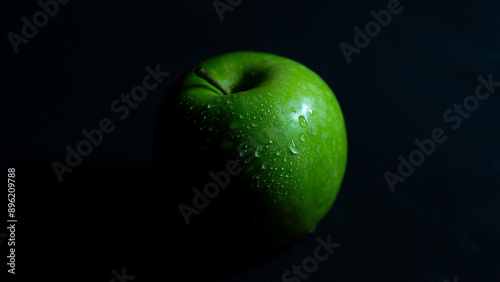 Grüner Apfel mit Wassertropfen in stimmigem Licht