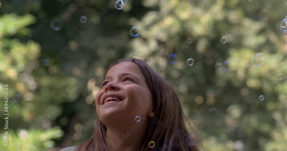 Girl playing with bubbles, smiling and enjoying the magical moment in slow-motion at 800 fps, surrounded by nature on a sunny day Girl playing with bubbles, smiling and enjoying the magical moment in slow-motion at 800 fps, surrounded by nature on a sunny day