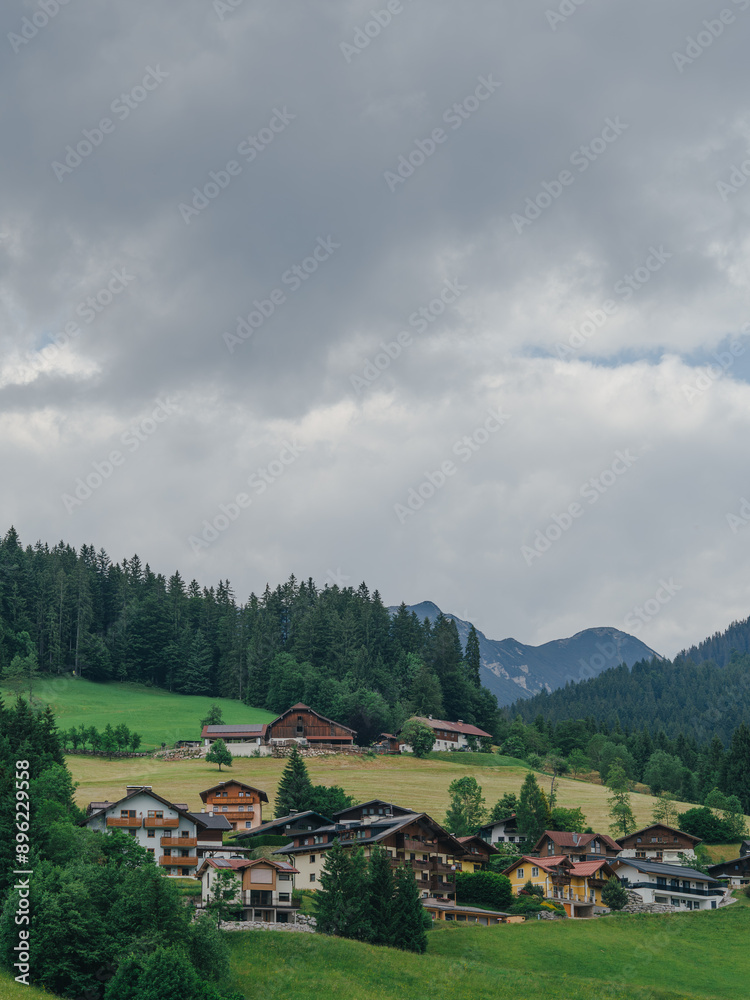 Idyllic alpine village nestled in lush green valley on overcast day Idyllic alpine village nestled in lush green valley on overcast day