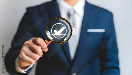 Businessman hand holding magnifying glass focusing standard quality control certification