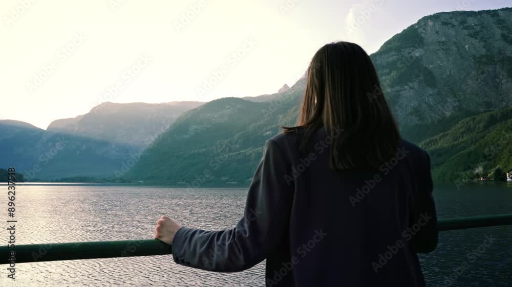 Camera approaches young woman lost in thought at beautiful sunset with view of lake and mountains Camera approaches young woman lost in thought at beautiful sunset with view of lake and mountains