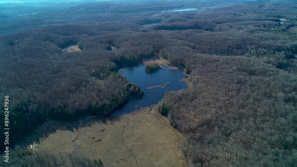 Aerial view flying away from a large pond and forest on a sunny day in the fall Aerial view flying away from a large pond and forest on a sunny day in the fall