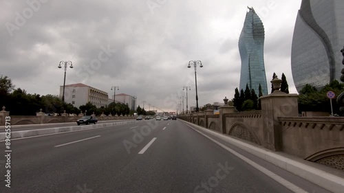 The central road leads through modern architecture towards the glowing center of Baku at dusk. Symbolizes progress, urban life, and a journey into the city.