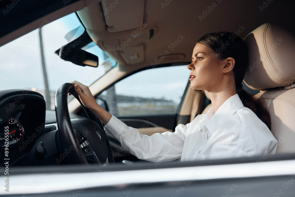 A woman, eyes closed, sits in the driver's seat of a car, one hand resting on the steering wheel, suggesting fatigue or meditation during a break from driving A woman, eyes closed, sits in the driver's seat of a car, one hand resting on the steering wheel, suggesting fatigue or meditation during a break from driving