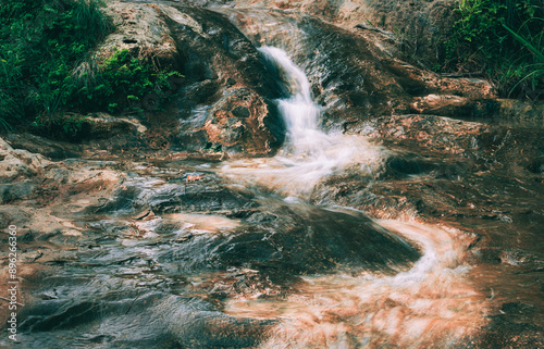 slow shutter speed shot of rushing water over reddish rocks