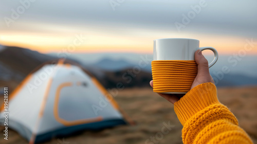 hand holding a coffee  cup  mountain landscape at sunrise and camping tents photo