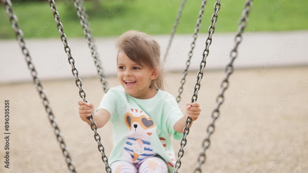 Little girl is riding on a swing. Child is playing on the playground. Little girl is riding on a swing. Child is playing on the playground.