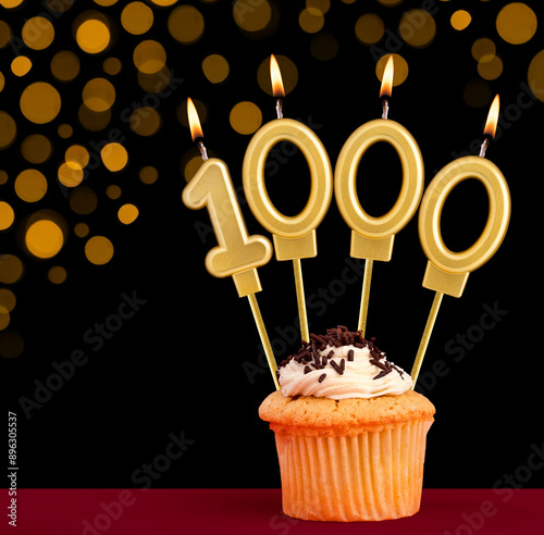 Birthday candle with cupcake - Number 1000 on black background with out of focus lights photo