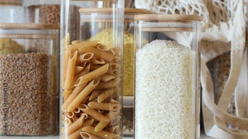 Close-up of glass jars with rice and pasta. Reusable eco-friendly food storage jars. Vertical movement. Zero waste concept