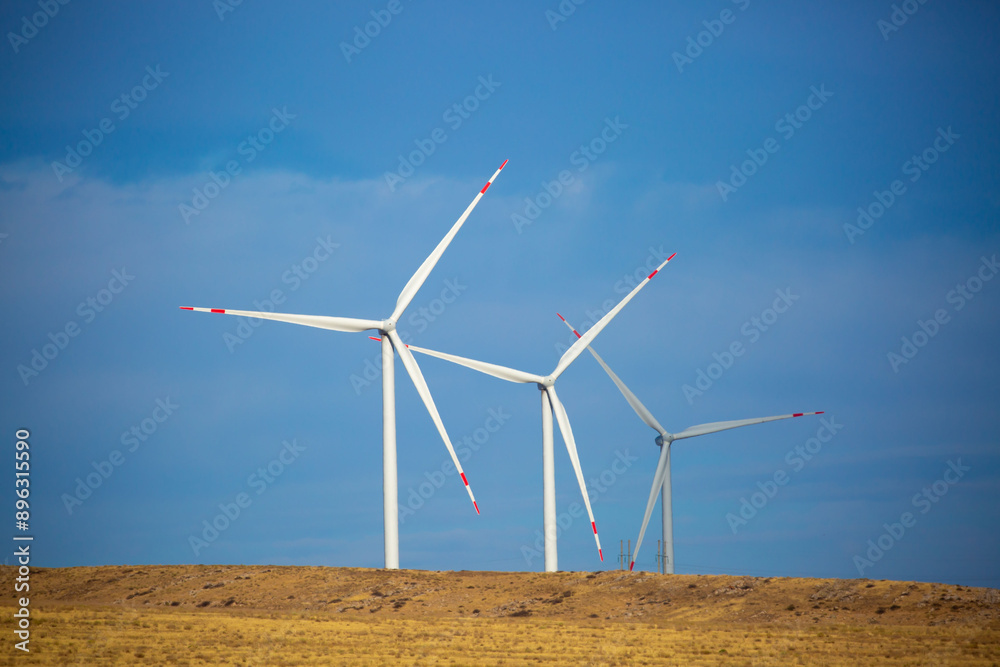 Fleet of power generators in motion. The blades of the wind farm rotate against the sky. The concept of extracting electricity from renewable sources. Wind turbine to generate electricity. Fleet of power generators in motion. The blades of the wind farm rotate against the sky. The concept of extracting electricity from renewable sources. Wind turbine to generate electricity.