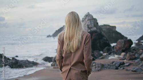 Calm girl contemplating ocean waves in evening. Attractive model turning camera