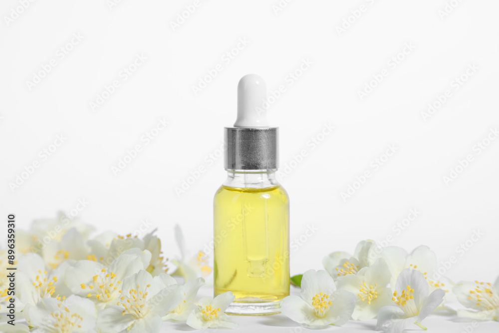 Essential oil in bottle and beautiful jasmine flowers on white background Essential oil in bottle and beautiful jasmine flowers on white background