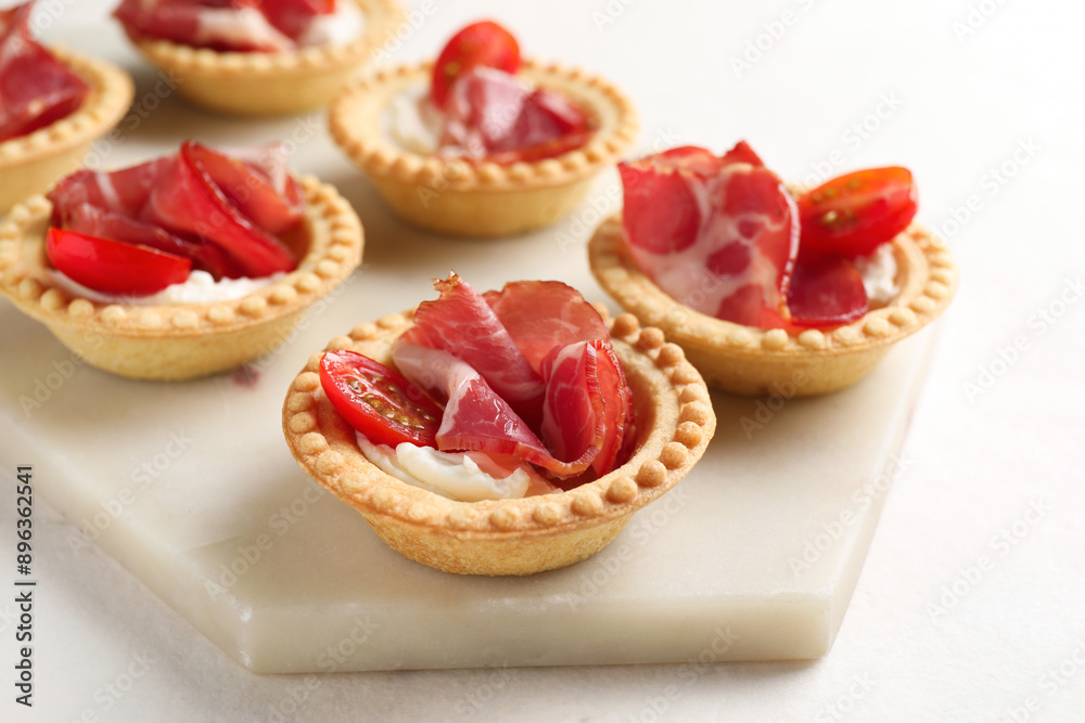 Delicious canapes with jamon, cream cheese and cherry tomatoes on light table, closeup Delicious canapes with jamon, cream cheese and cherry tomatoes on light table, closeup