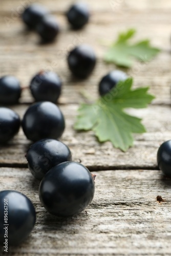 Ripe blackcurrants and green leaves on wooden table, closeup