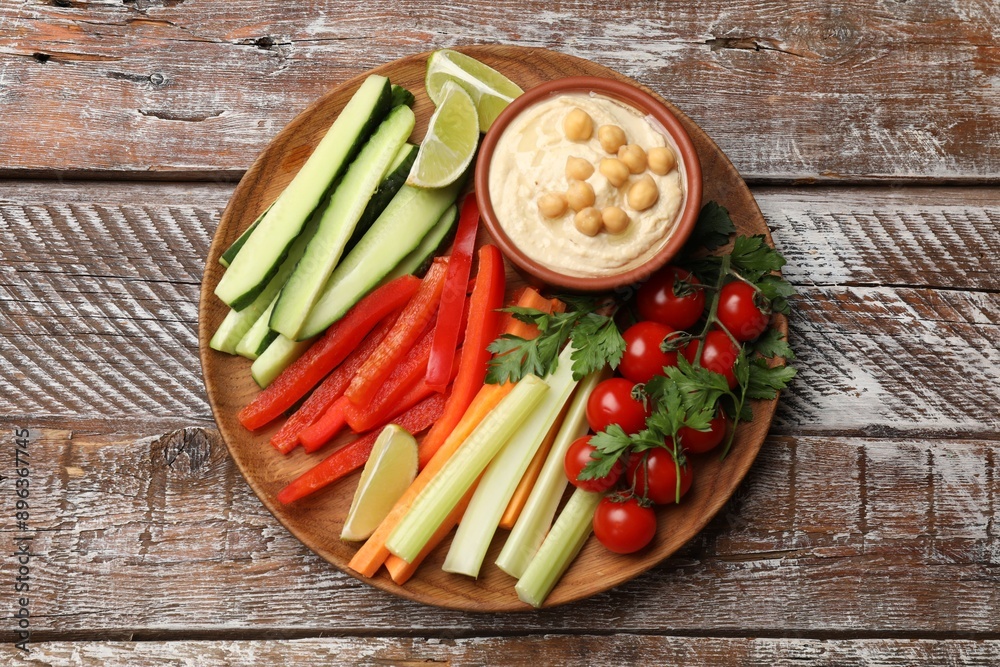 Tasty homemade hummus served with different vegetables on wooden table, top view Tasty homemade hummus served with different vegetables on wooden table, top view
