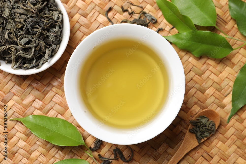 Fototapeta premium Refreshing green tea in cup, spoon and leaves on table, flat lay