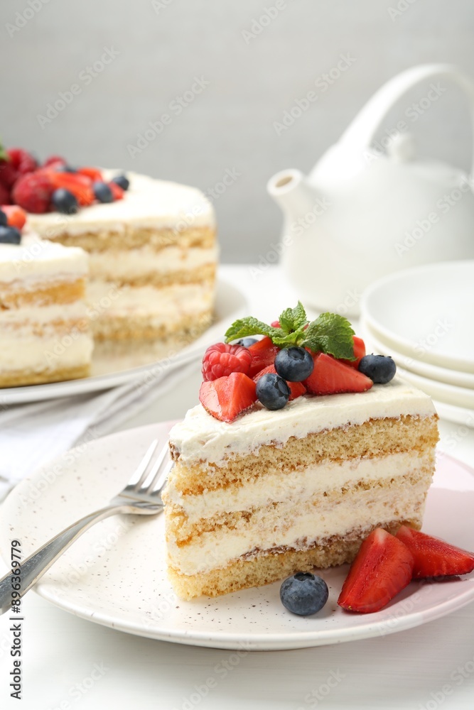 Tasty sponge cake with fresh berries and mint served on white table Tasty sponge cake with fresh berries and mint served on white table